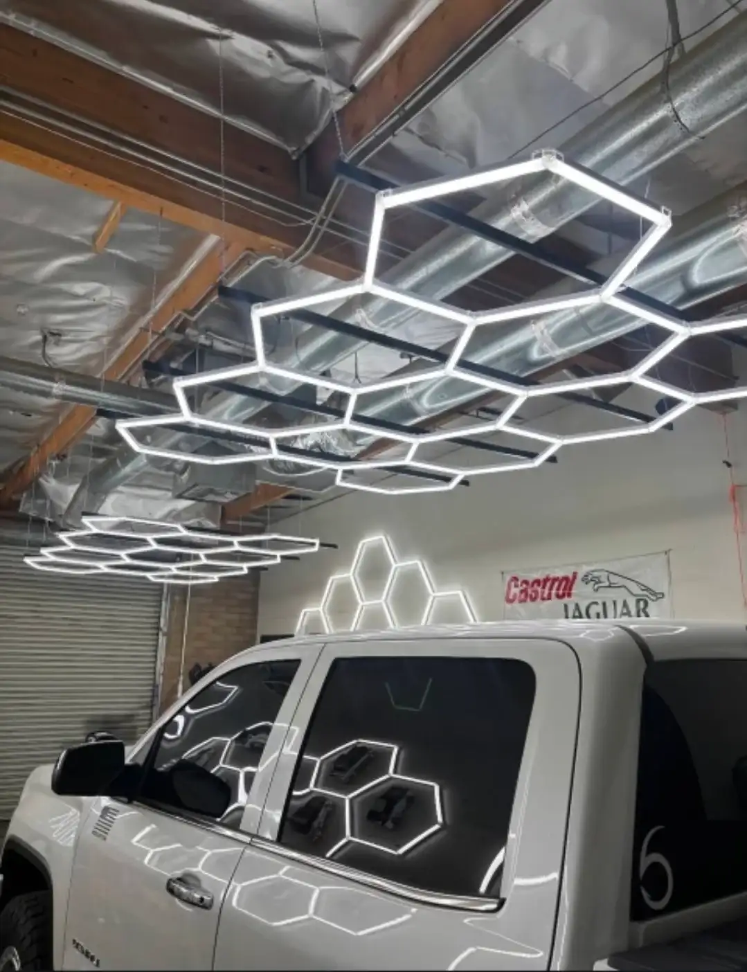 Interior of Mr. Glassworks Tempe shop showing hexagonal LED ceiling lights and a white truck in the bay