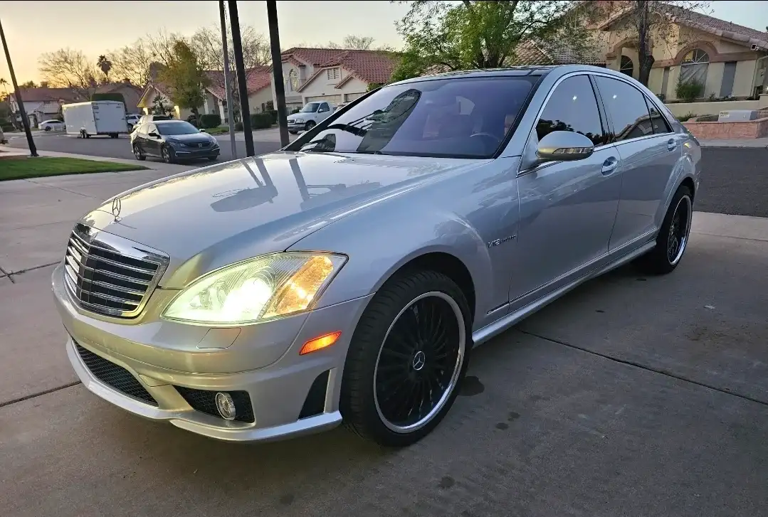 Silver Mercedes-Benz S-Class with dark tinted windows photographed at dusk in a residential area