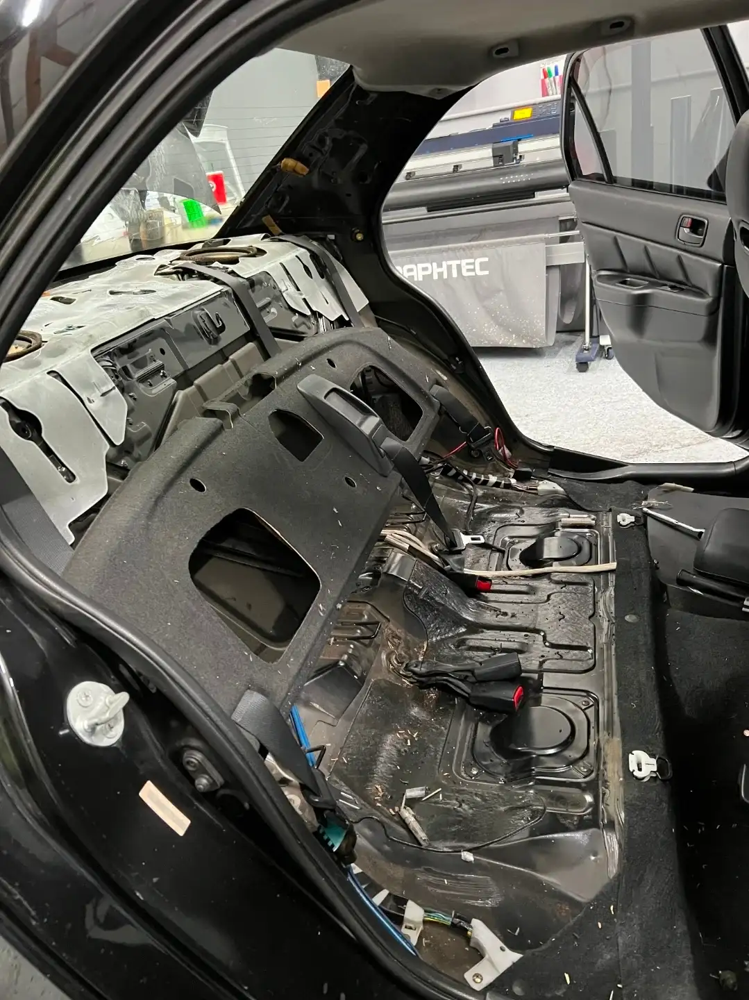 Vehicle interior with dashboard completely removed during a windshield replacement showing exposed firewall