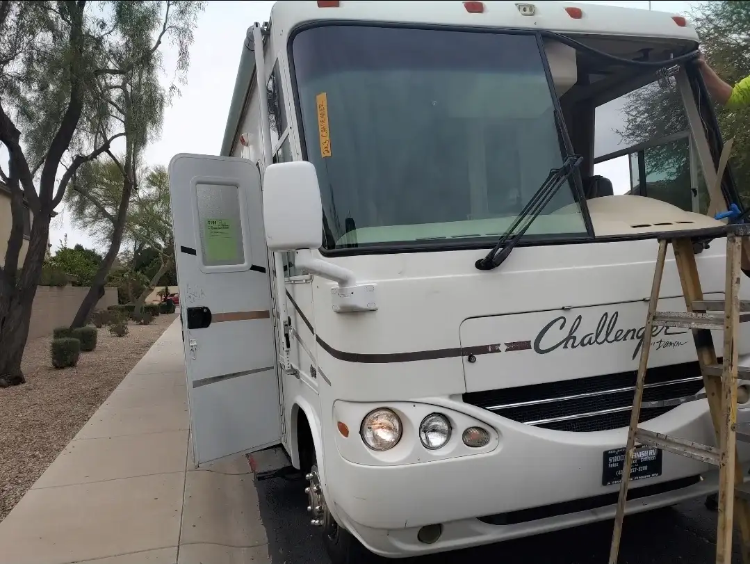 Damon Challenger Class A motorhome getting a new windshield installed at a residential driveway