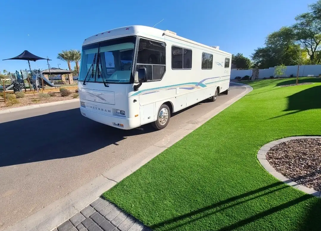 White Class A motorhome with new windshield parked on a residential street in an Arizona neighborhood