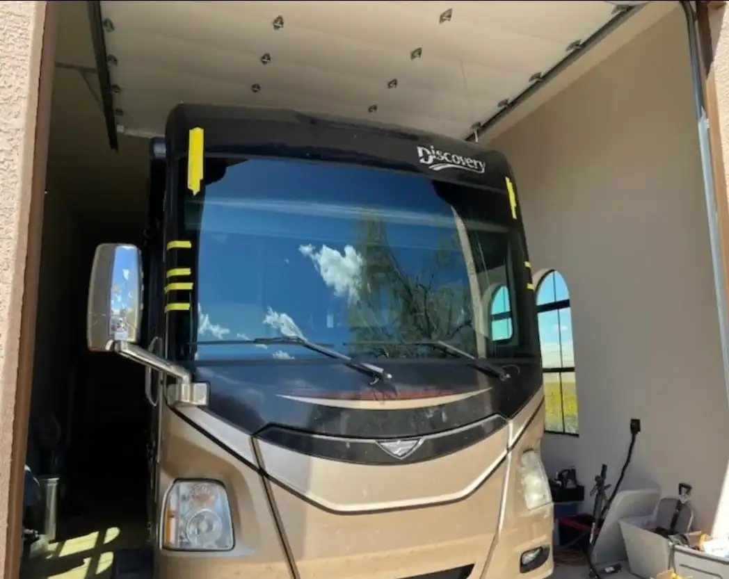 Fleetwood Discovery motorhome with newly installed windshield and yellow retention tape in an RV garage